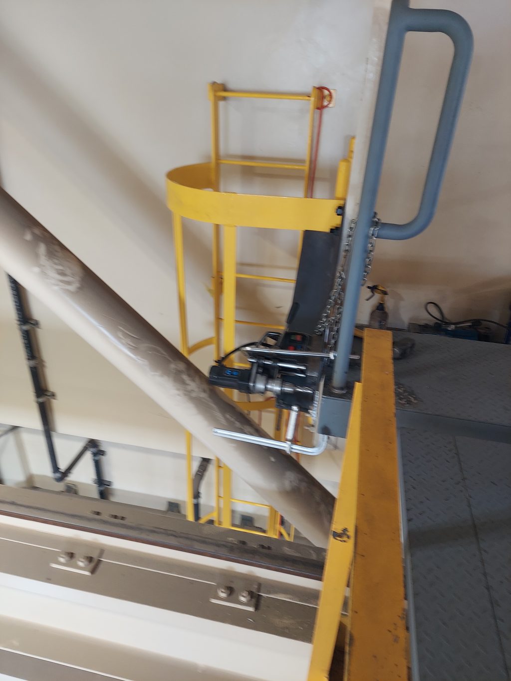 Yellow steel caged ladder and platform guard railing installed inside an industrial facility