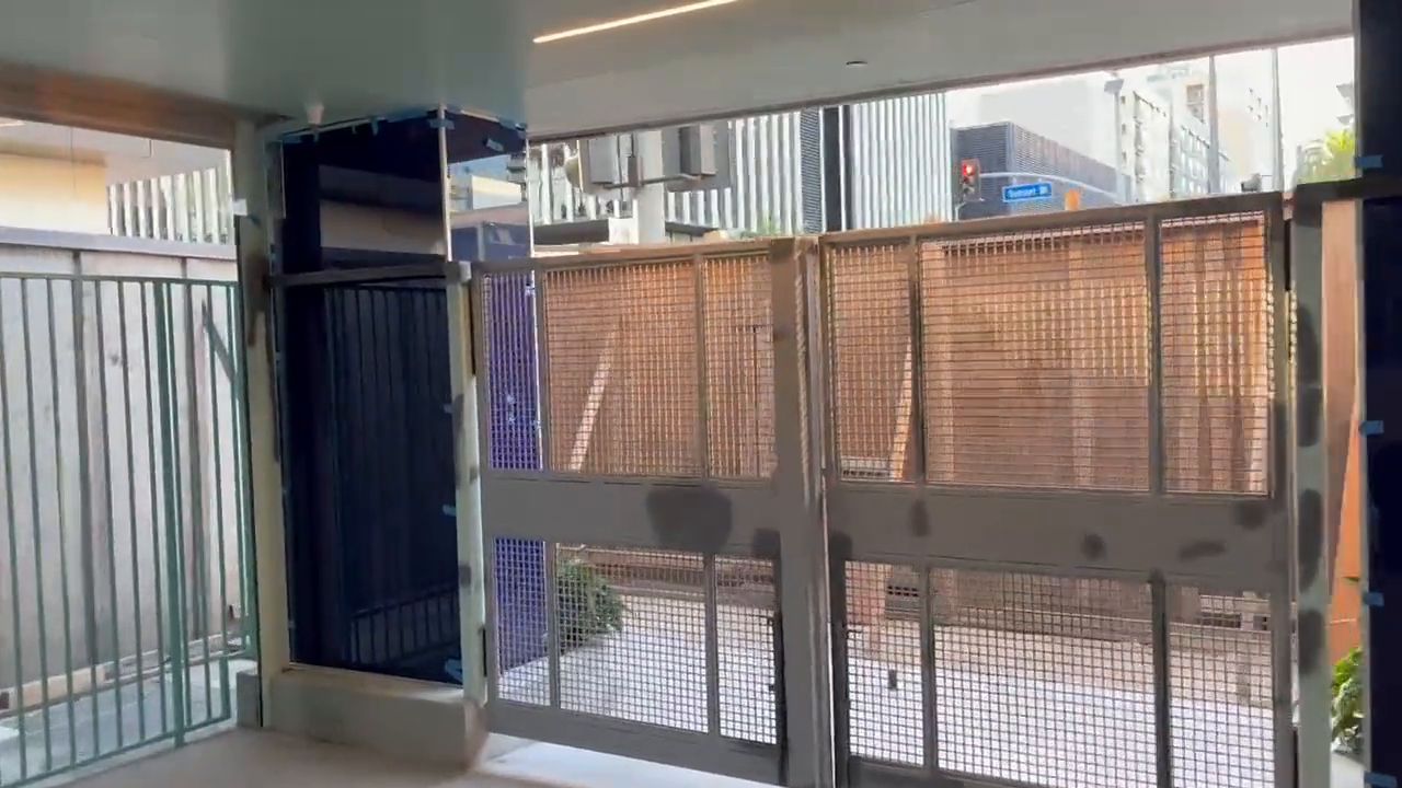 Walkthrough of installed steel-framed mesh railing and screen panels along a covered commercial walkway