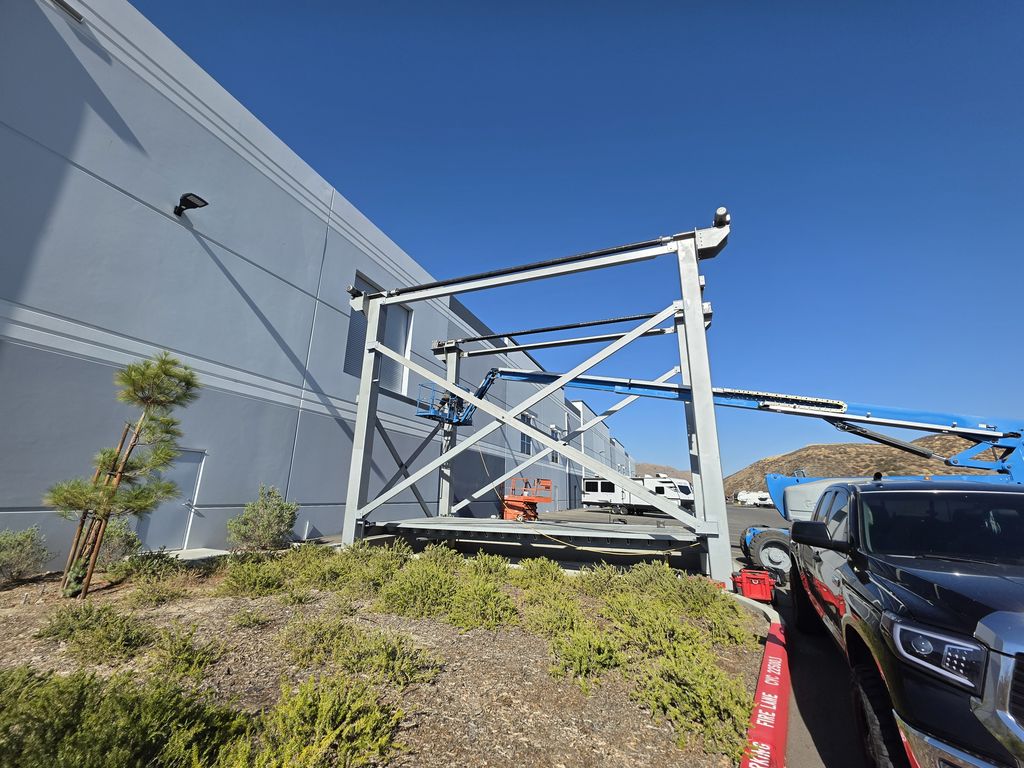 Side view of the finished cross-braced steel frame structure next to a commercial building, landscaping in the foreground